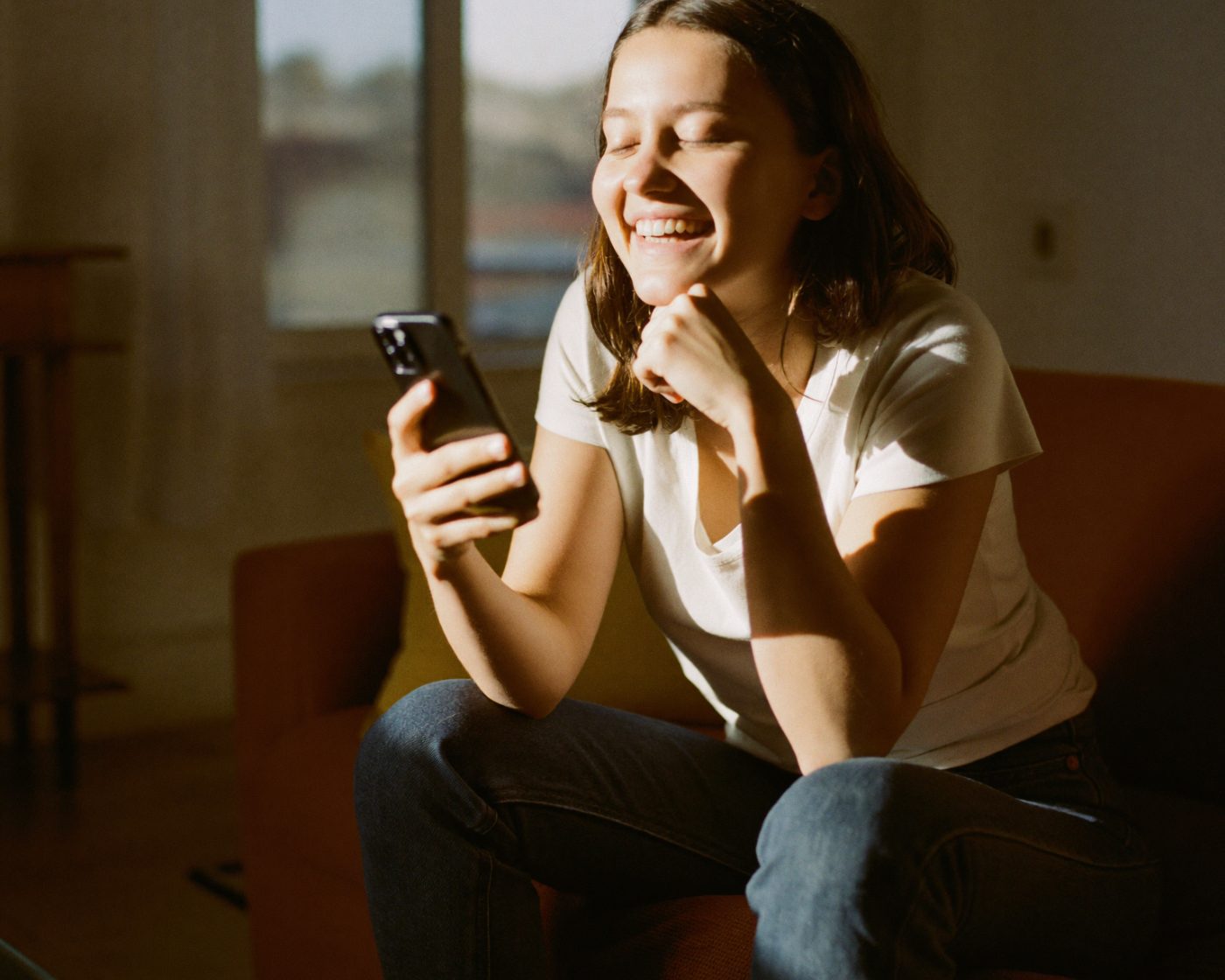 A woman smiling at her phone after checking her loan options